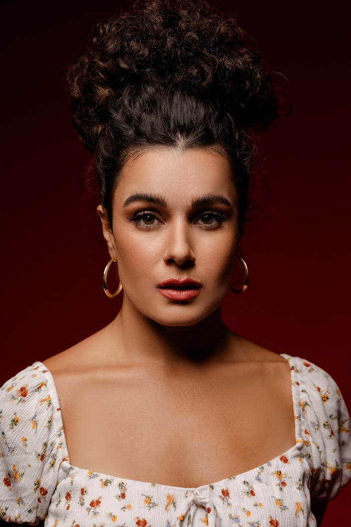 Striking portrait of a woman against a bold red background, highlighting elegance.