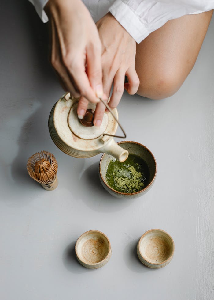 Overhead view of a traditional matcha tea ceremony with ceramic cups and bamboo whisk.
