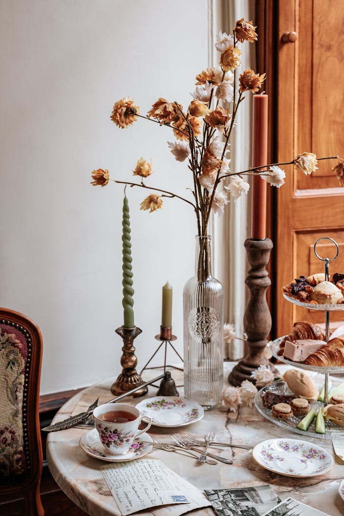A beautifully arranged vintage high tea setup with floral decorations and pastries.
